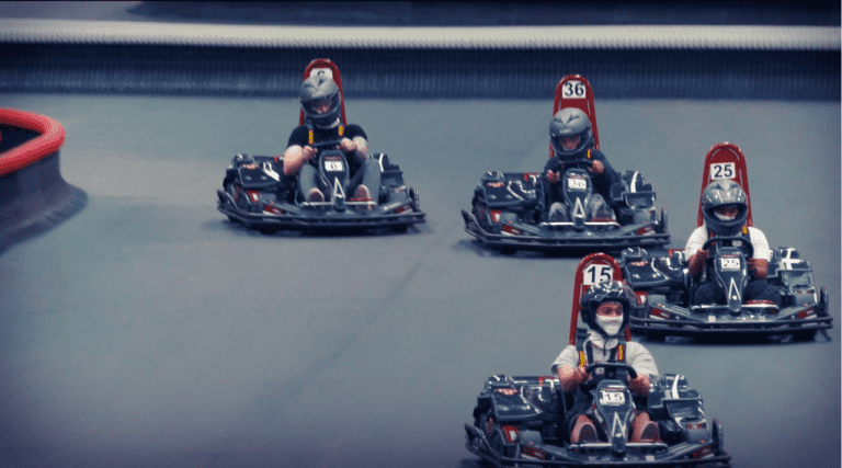 Go-kart race with four drivers on indoor track.