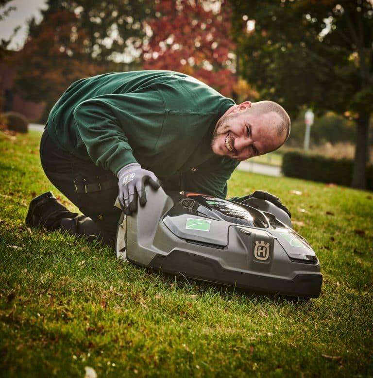 Vicevært udfører service på robotplæneklipper
