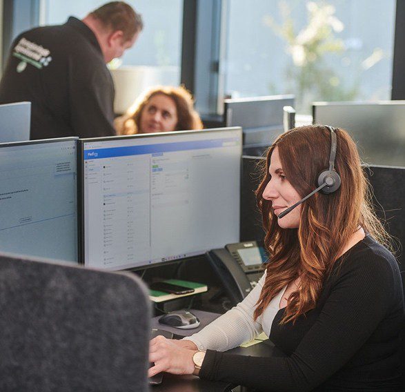 Effektiv kundeserviceagent med headset håndterer opkald i et professionelt kontormiljø