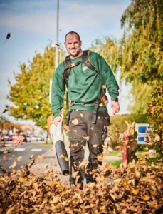 Vicevært bruger løvblæser til efterårsoprydning af fortov, Ejendomsservice