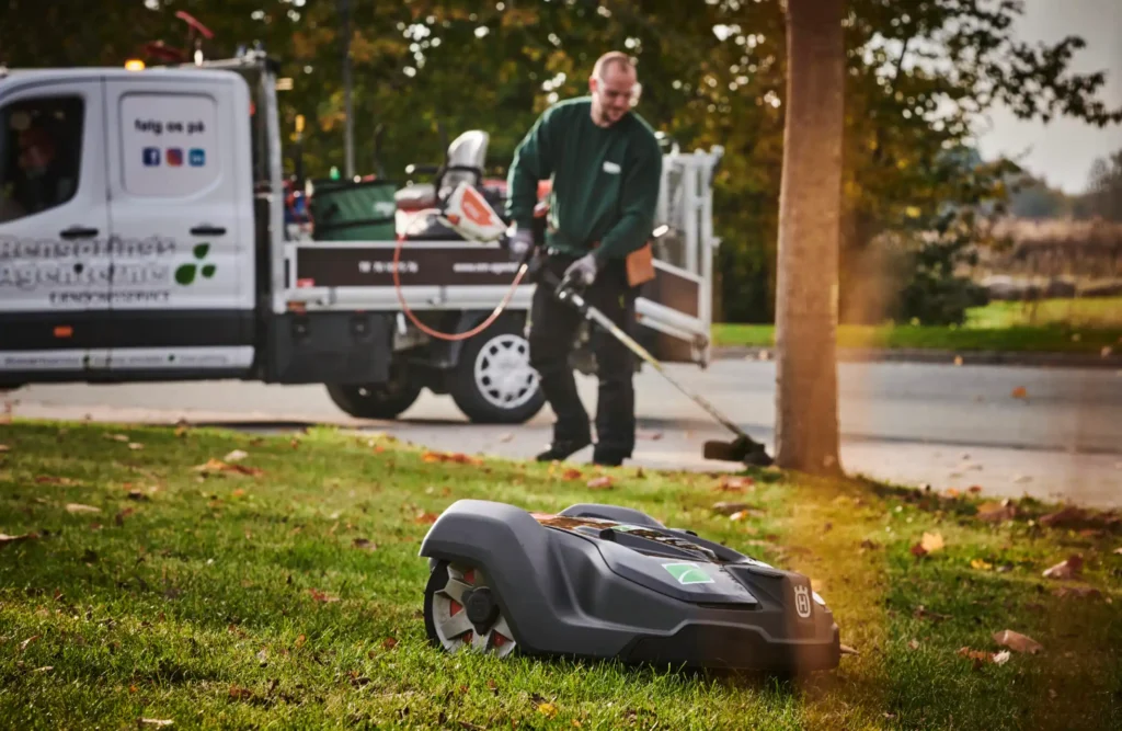 Vicevært og robotplæneklipper der arbejder
