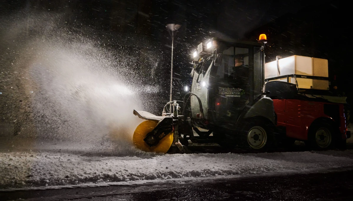 Snerydning om natten med specialkøretøj fra ejendomsservice rydder sne fra dansk landevej.