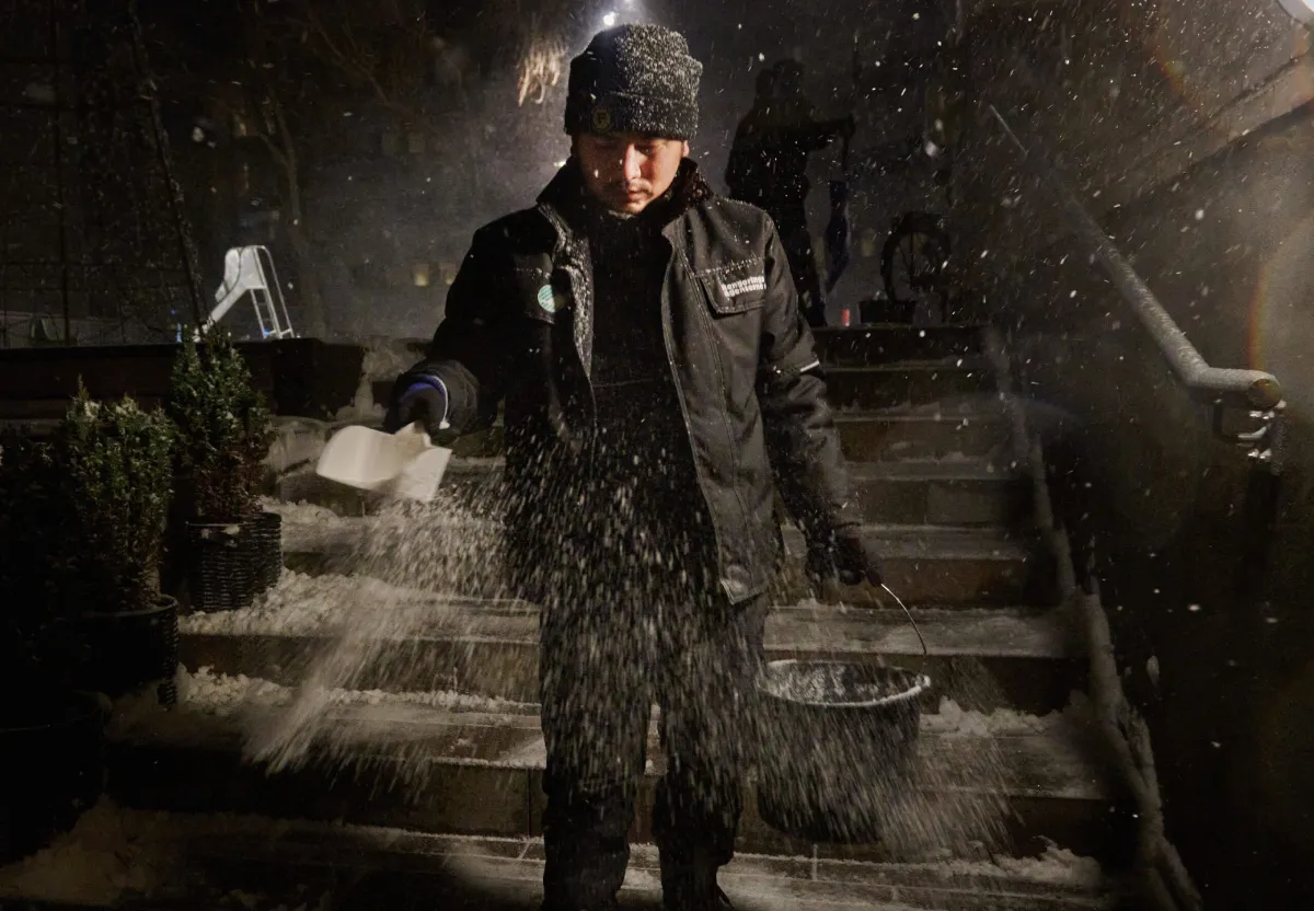 Medarbejder salter trappe om natten under snevejr som del af professionel snerydning.